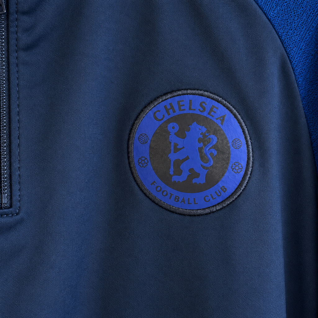 Close-up of a Chelsea Football Club embroidered patch on a navy blue jacket, showing the club's lion crest and text.