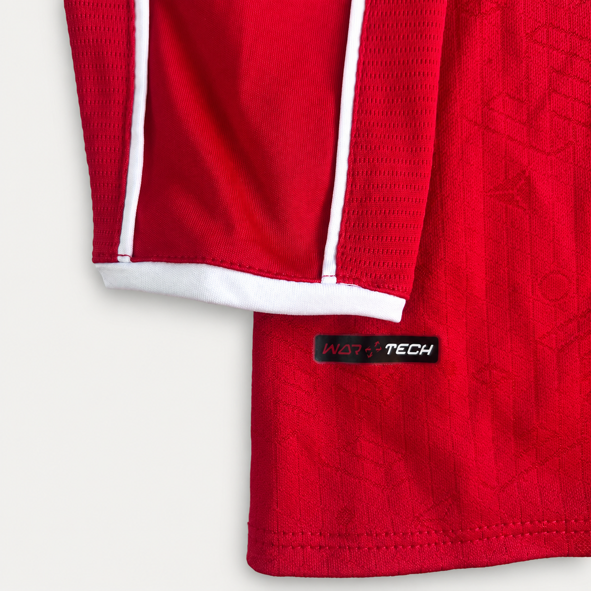 Close-up of a red athletic jersey sleeve with white piping and a white ribbed cuff, featuring a black WATERTECH label near the hem.