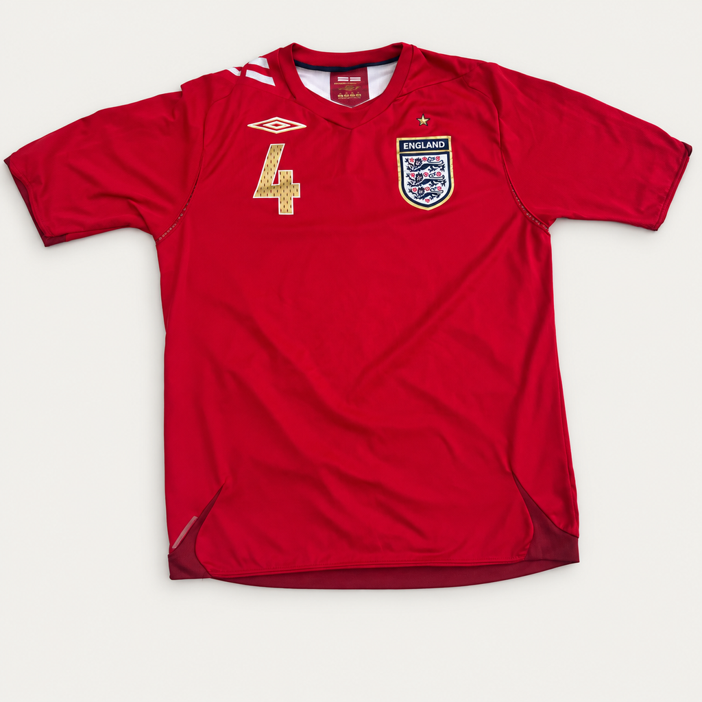 A red short-sleeve England soccer jersey with the number 4 on the chest, featuring the Umbro logo and the England crest, laid flat against a light gray background.