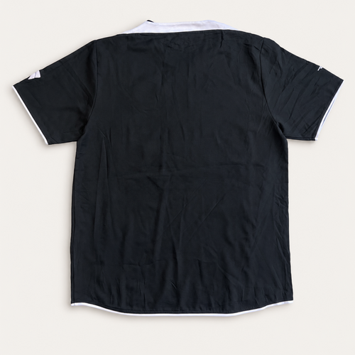 A black short-sleeve t-shirt with white contrast piping along the collar, sleeve cuffs, and hem, laid flat on a light beige background.