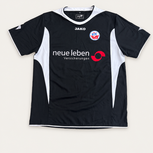 A JAKO black and white soccer jersey with red and blue details, featuring the 'neue leben Versicherungen' sponsor logo on the front, laid flat against a light beige background.