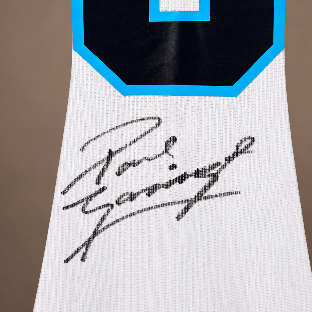 Close-up of a white jersey sleeve or lower body section with a black and bright blue number block at the top and a large black autograph across the front, reading Paul Gascoigne