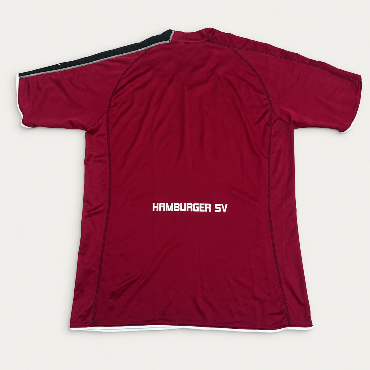A burgundy athletic windbreaker jacket with 'HAMBURGER SV' printed vertically in white on the chest, laid flat on a light gray background.