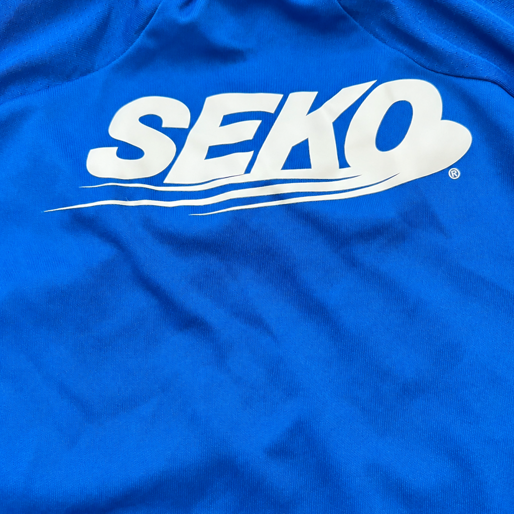 A close-up of a bright blue fabric surface with a large white SEKO logo printed across it.