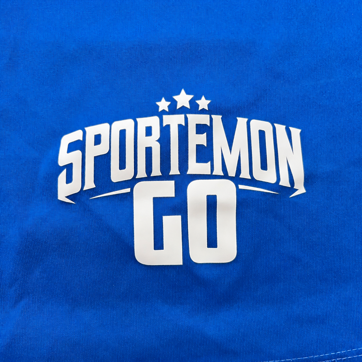 A close-up of a royal blue garment featuring a bold white graphic print that reads 'SPORTEMON' with three stars underneath.
